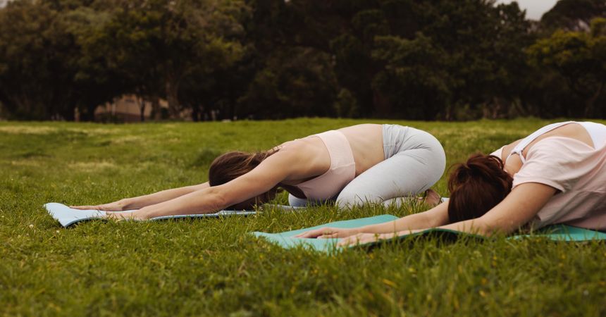 Two fitness women doing yoga in a park