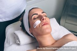 Woman lying with eyes closed having a clay mask applied 4267g3