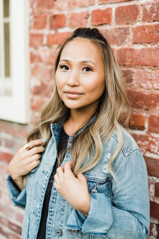 Woman in blue denim jacket leaning on brown brick wall