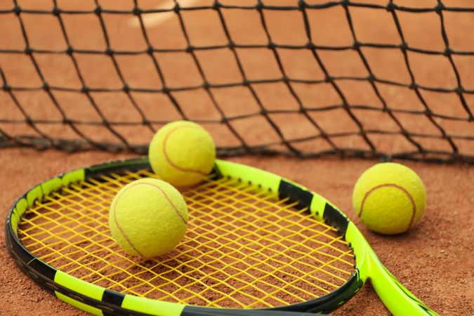 Tennis racquet with tennis balls on clay court