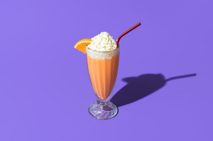 Orange milkshake isolated on a purple background