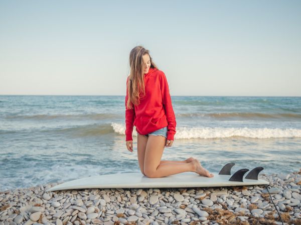 Cheerful woman sitting on surfboard