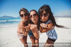 Group of women blowing kisses to camera at the beach 4jkBxb