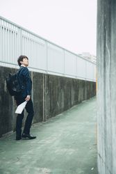 Man in dark in dark suit standing on sidewalk