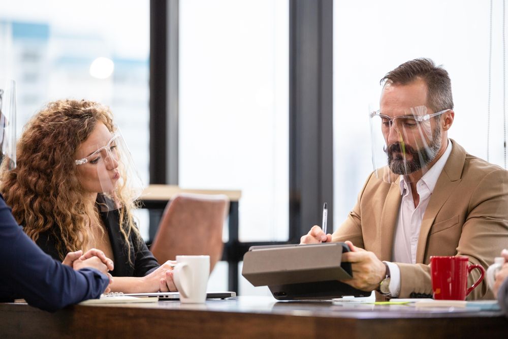 Male and female colleague looking over documents on digital tablet