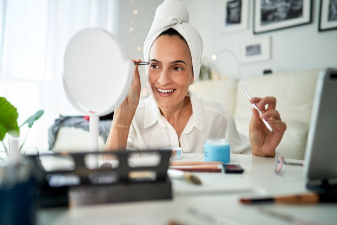 Smiling woman shaping eyebrows with tweezers