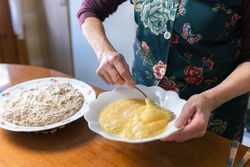 Older woman mixing eggs to prepare croquettes at home