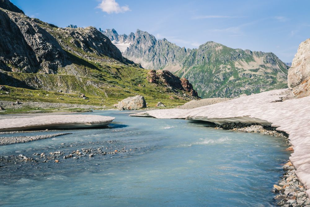 Shallow river flowing along rocky shore in bright day