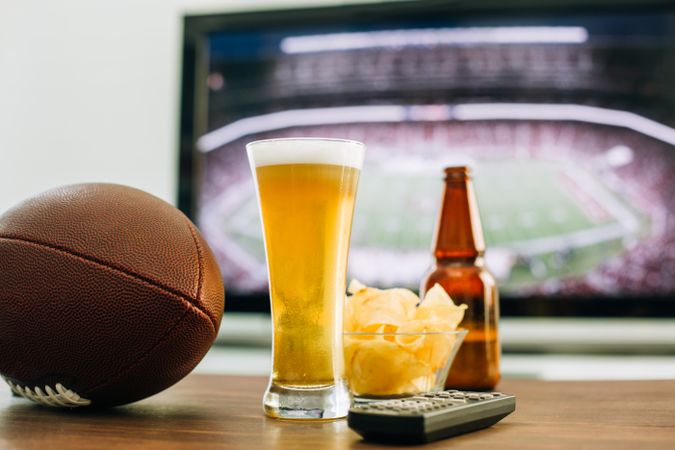 Beer and snacks prepared for watching american football on TV
