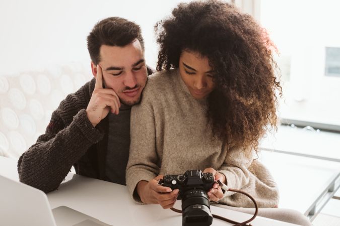Multiracial couple looking at photo camera at home