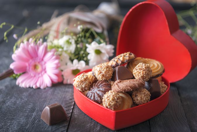 Delicious sweets in a red box and flowers on rustic table