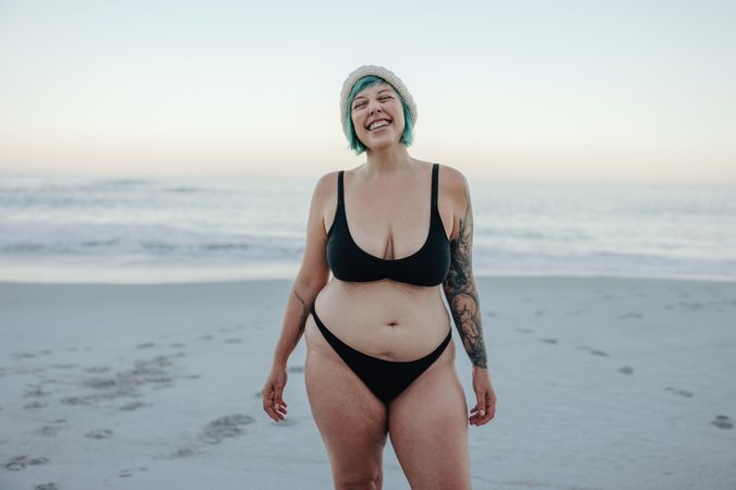 Excited swimmer smiling with her eyes closed while standing by the sea