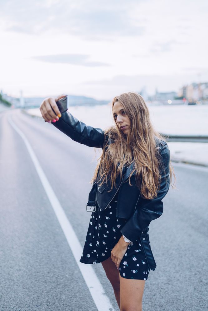 Long haired stylish woman taking selfie with smartphone