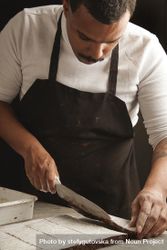 Black man in apron slicing brownies 0PBQm4
