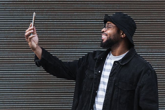 Laughing Black man taking selfie on smartphone
