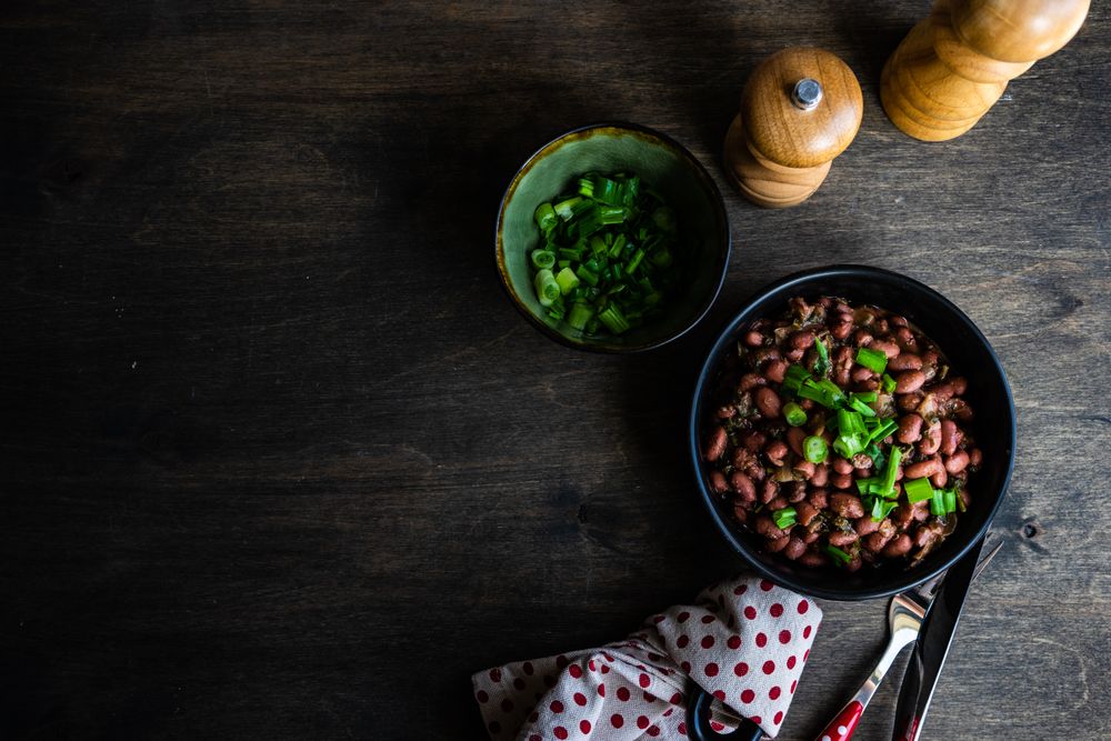 Top view of traditional Georgian lobio dish with green onions on wooden table with copy space