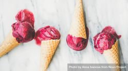Four cones of dark berry ice cream on marble slab, horizontal composition 5QK6Gb