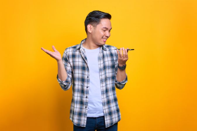 Asian male talking on speaker phone in studio shoot with hand gesture