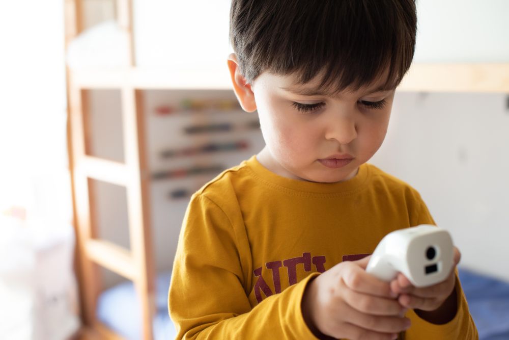 Boy holding thermometer in his bedroom