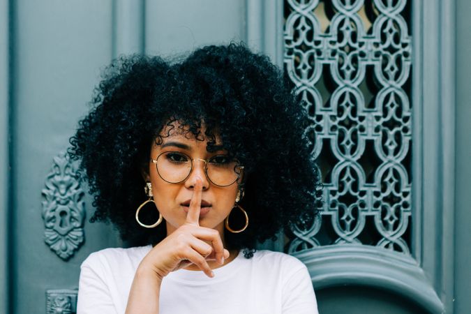 Stylish female by green door asking for silence