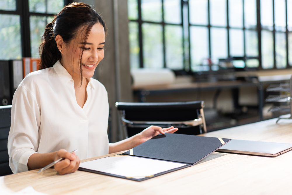 Smiling woman reading through report at work