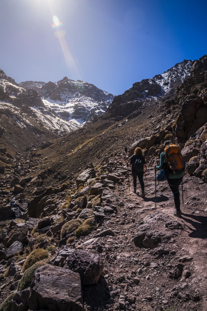 Tourists walking up mountain slope at sunny day
