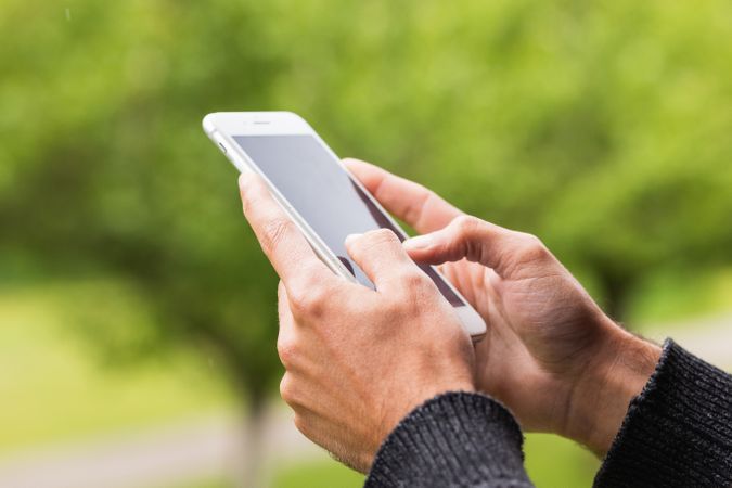 Anonymous man browsing on mobile phone on terrace