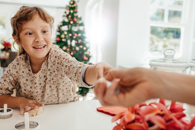 Little girl making cookies for Christmas with adult