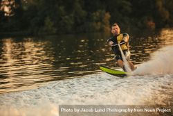 Skilled water skier using both hands to grip tow rope from boat sailing across lake bxN8v5