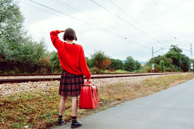 Woman looking at approaching modern train on railroad