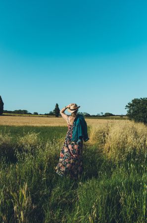 Female farmer with hat looking at her wheat crop.