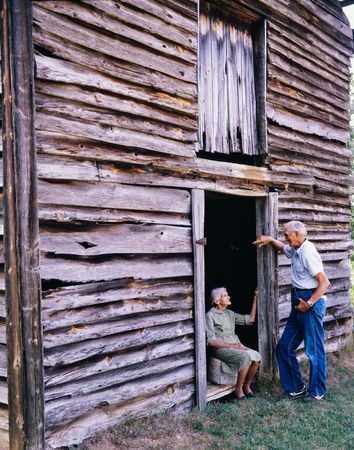 Older couple smiling and talking at wooden barn door, North Carolina
