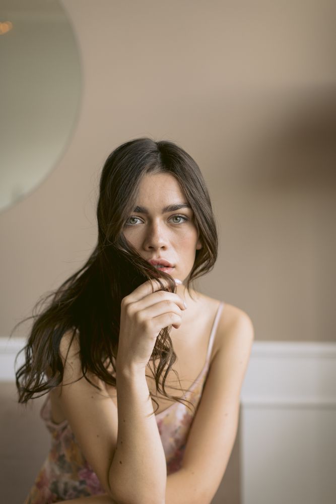 Portrait of woman with long brown hair draping it over the lower part of her face