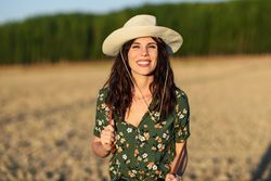 Smiling female in field wearing floral shirt and straw hat