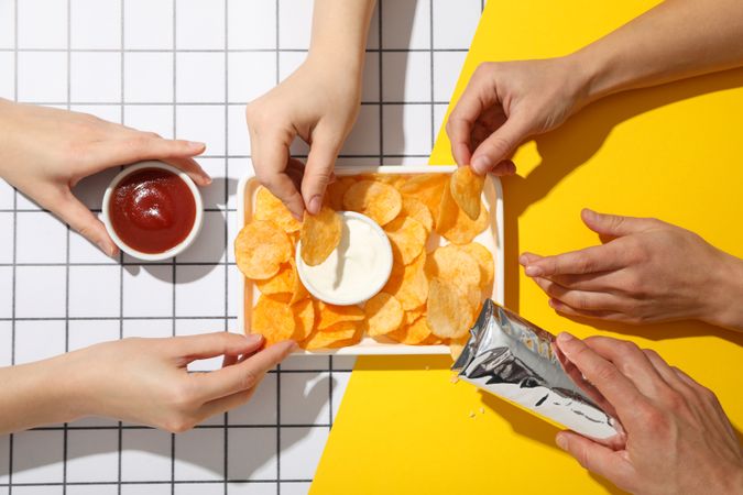 Potato chips in a bowl with sauces on a light background