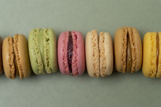 Line of colorful tasty macaroons over a green background