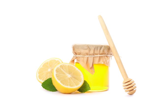 Dipper, lemons and glass jar with honey isolated on studio background
