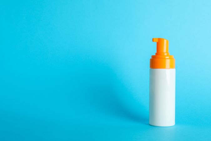 Sunscreen spray on color background, space for text