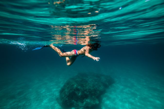 Unrecognizable boy snorkeling in mask and flippers in seawater