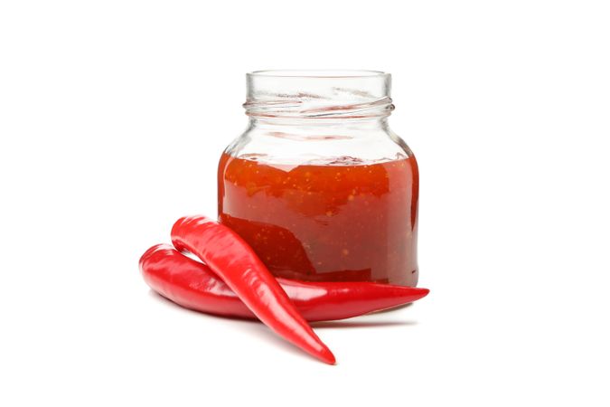 Chilli pepper and glass jar of sauce isolated on blank background