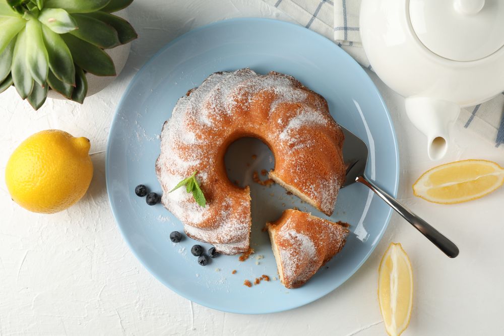 Cake with powdered sugar, blueberry and mint on plain background, top view