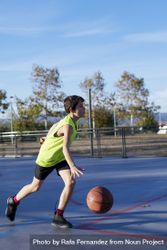 Teenager dribbling basketball on an outdoors court 5qmOE5