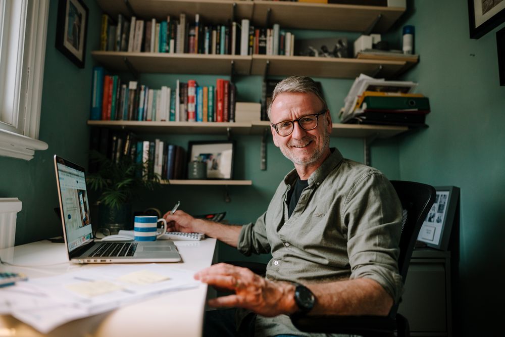 Mature smiling man working in comfortable home office with coffee cup