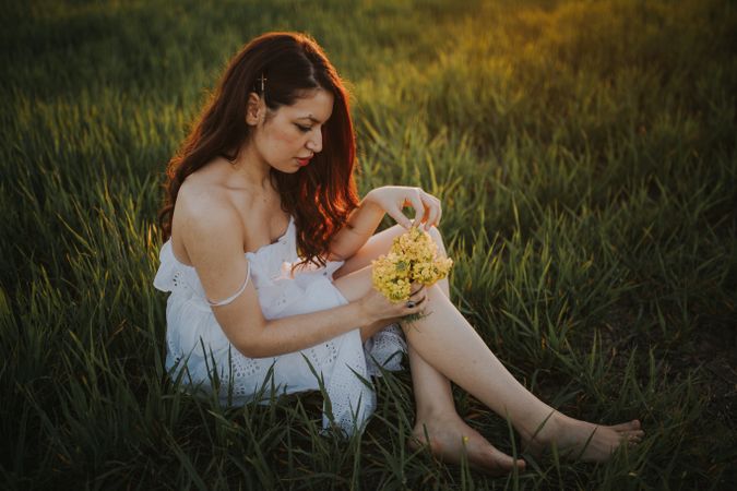 Barefoot woman with flowers in meadow
