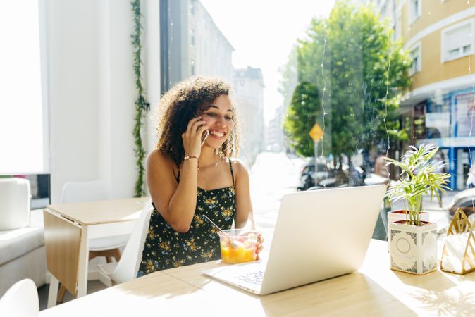 hispanic female with laptop enjoying healthy drink in cafe