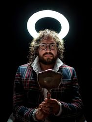 Serious man with glowing fake nimbus holding mirror and looking at camera