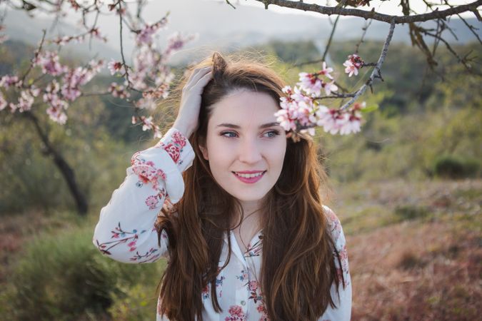 Young happy woman between trees in garden