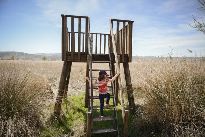 Field with wooden stairs with child climbing up for view