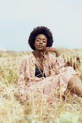 Woman in pink floral dress sitting on yellow grass field