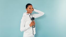 Fit Black woman with water bottle on blue background